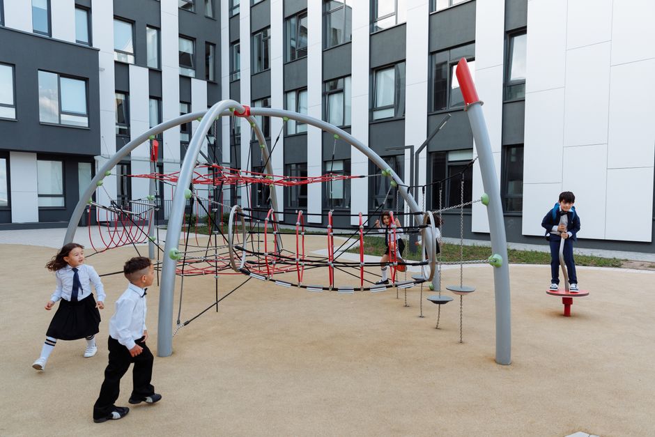 Children in uniform on a climbing frame in the school courtyard