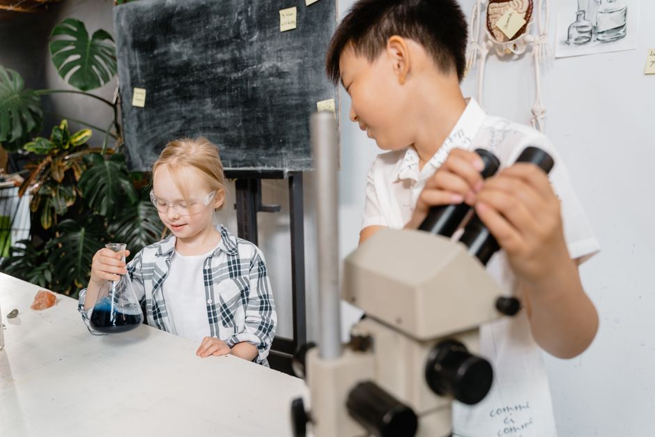 Two students working with a flask and microscope in the science lab