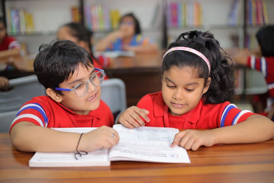 Two primary students reading a workbook together in the library