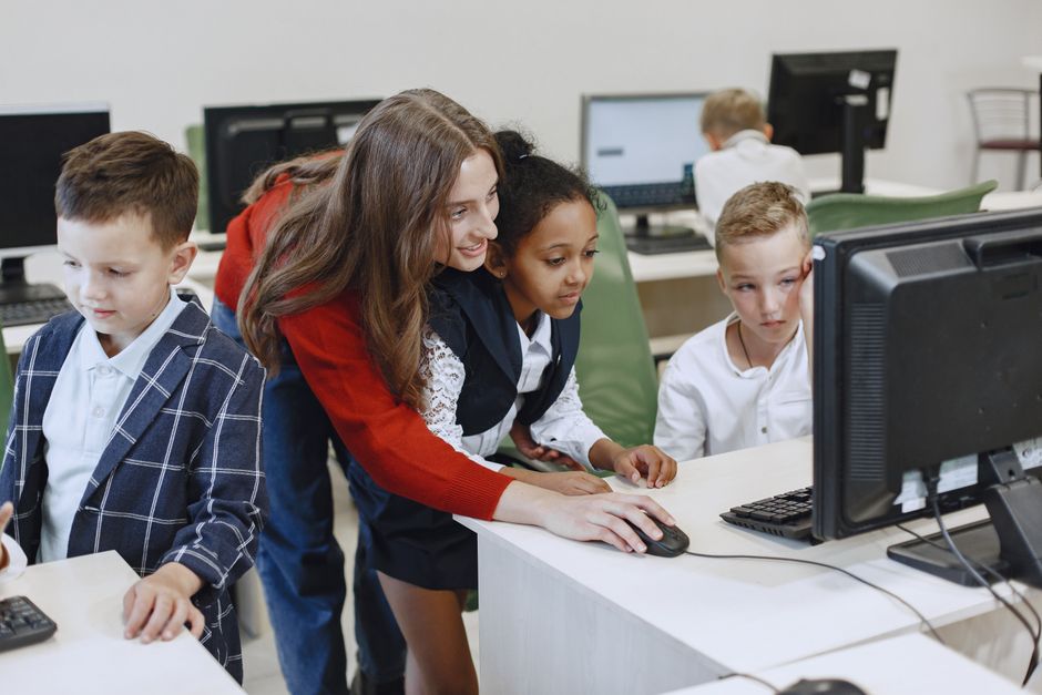 A teacher helping students at computers in the lab